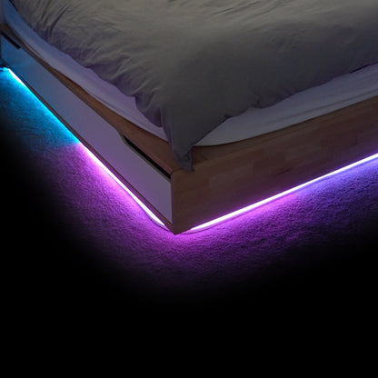 Bright LED strip lights under the bed, creating a vibrant bedroom glow